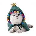 Cat wearing a green Christmas tree cape with pompoms and a star