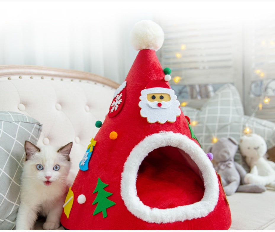 Cat in a red Santa hat shaped cat bed next to a green tree version