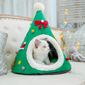 Cat in a red Santa hat shaped cat bed next to a green tree version