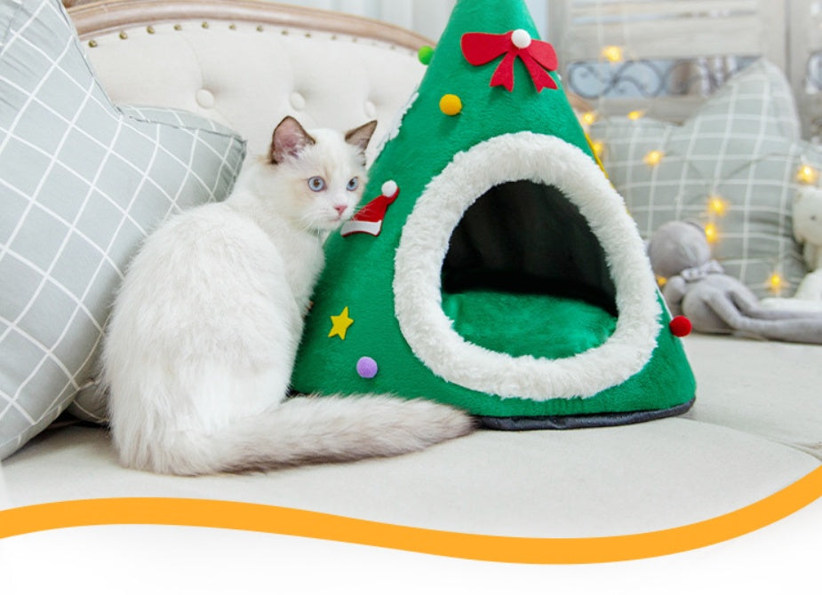 Cat in a red Santa hat shaped cat bed next to a green tree version